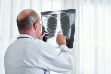 Naklejka na ściany i meble Radiologist examining lungs x-ray of patient and searching for signs of cancer