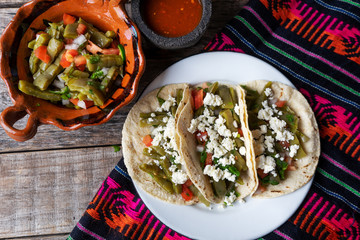 Mexican nopal cactus salad and tacos with cheese on wooden background