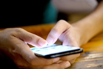Hand of woman uses and looks smartphone in the bedroom without light and darkness.