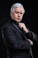 Mature man in black suit looking at the camera with a hypnotic look.