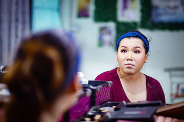 Mirror reflection of Asian woman doing makeup