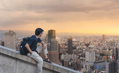 a man with backpack looking at city skyline view in sunrise