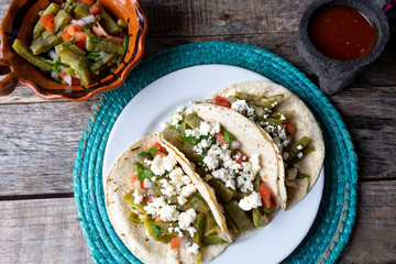 Mexican nopal cactus salad and tacos with cheese on wooden background