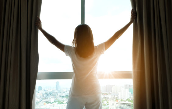 Morning of a new day, Women wake up from bed. In the morning, she opens the curtains in her bedroom for fresh air and natural morning sunshine.