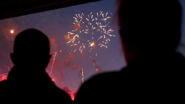 Colorful firework explodes beautifully close up in city sky front people 4K.