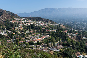Naklejka premium Upscale hillside homes near Los Angeles in Glendale California with morning mist and San Gabriel mountains in background.