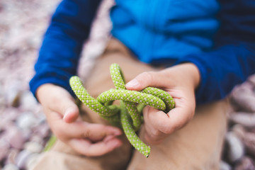 A child learns to knit a knot from a rope.