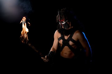 Shirtless male in wolf mask with torch view