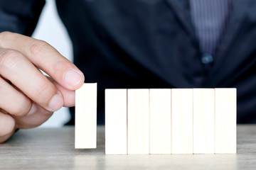 Steps of success for business or investment. Business man is arranging wood block to increase high,...