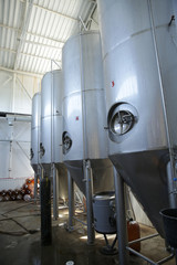 shiny tanks or barrels at a beer and wine factory. Industry Brewing and winemaking. Equipment for the winery and brewing industrial interior of a factory