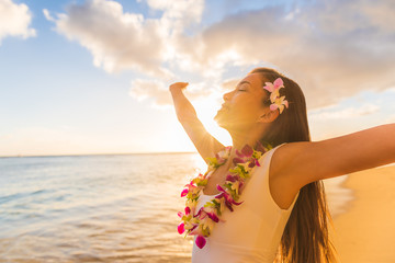 Hawaii hula luau woman wearing hawaiian lei flower necklace on Waikiki beach dancing with open arms free on hawaiian vacation. Asian girl with fresh flowers hair, traditional polynesian dance. - obrazy, fototapety, plakaty
