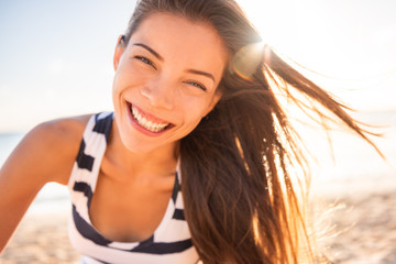 Happy Asian woman smiling in sun flare beach natural beauty model with perfect teeth laughing of...