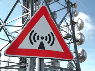 Metal sign with danger of electromagnetic waves. Group of towers for telecommunications, television...