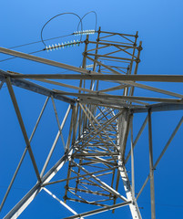 Supports high-voltage power lines against the blue sky. View from the bottom up