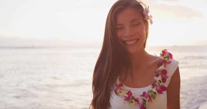 Woman portrait video looking at camera smiling. Hawaii woman wearing lei flower necklace on beach sunset for luau party or honeymoon wedding in Waikiki beach, Honolulu, holiday travel. SLOW MOTION