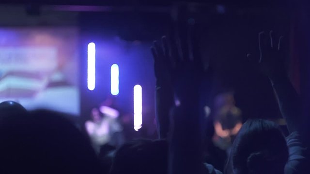Hands waving at concert in slow motion.
