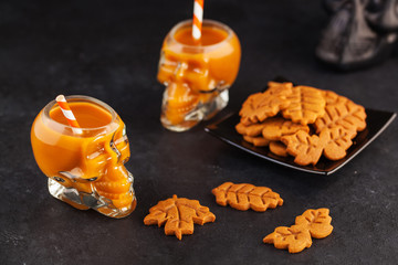Pumpkin drink in glass skulls and autumn cookies