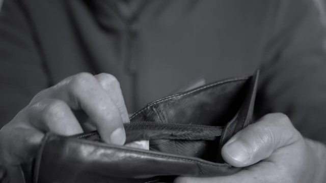 Caucasian worker with a missing finger opening  hes empty wallet, conceptual footage of underpaid labour in black and white.