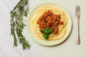 Spaghetti with bolognese sauce on a plate with metal fork.
