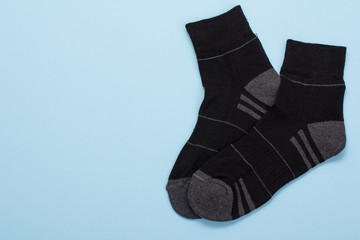 Pair of black woolen men socks on blue background.
