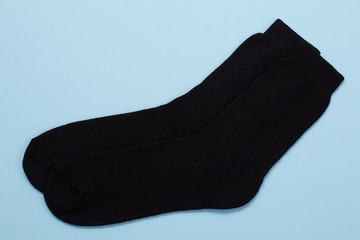 Pair of black woolen men socks on blue background.