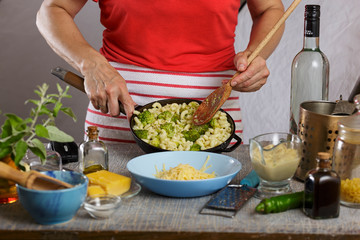 Cooking. Woman cooks pasta with broccoli and cheddar