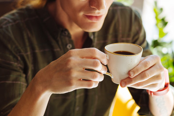 Close up of a cup with coffee in male hands