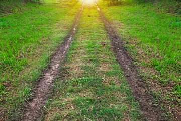 Pathway winding gravel road with green meadow and wheel marks on rode meaning the pathway to...