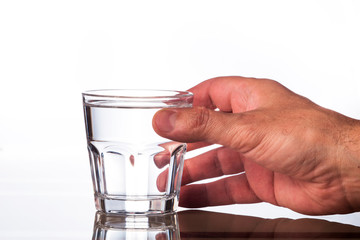 Hand holds a glass transparent glass with clean drinking water.