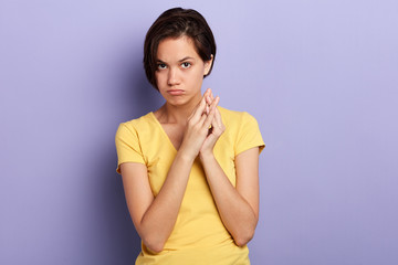 Fototapeta premium Offended young woman keeps palms together. close up portrait, isolated blue background, studio shot.