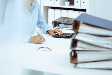 Unknown female bookkeeper or financial inspector calculating or checking balance, making report, close-up. Internal Revenue Service at work with financial document. Tax and audit concept