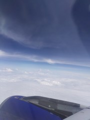 wing of airplane flying above clouds