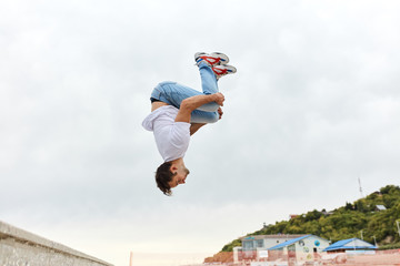 young man throwing a somersault outdoors, full length side view photo, copy space