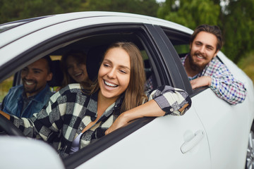 A group of happy friends are driving in a car.