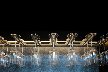 empty wine glasses hanging on rack in bar