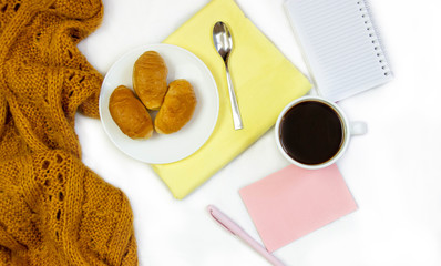 Breakfast in bed. Flat composition with coffee, croissants and a notebook for writing. Lifestyle concept frame. Top view on sheets