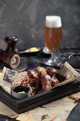 Tasty grilled ribs seasoned with spicy sauce and chopped fresh vegetables on an old rustic wooden cutting board with mustard