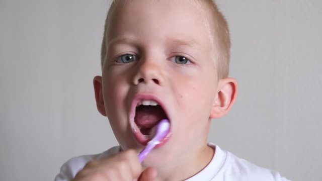 Little cute blonde kid boy is brushing teeth. Fun lifestile play dentist game. Children smile. Health care, dental hygiene