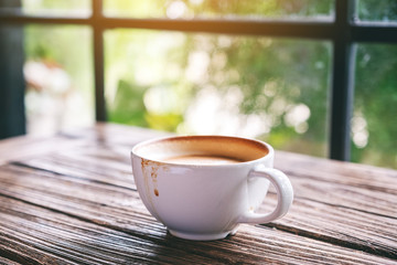 A white mug of hot coffee on wooden table in the morning