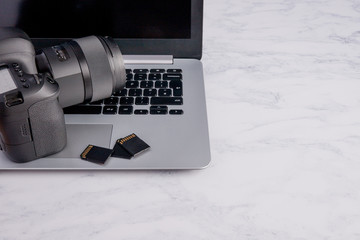Professional Photography Equipment. Camera and SD Cards next to Laptop. Transferring photos to...