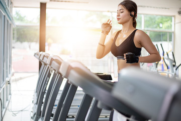 Asian women running sport shoes at the gym while a young caucasian woman is having jogging on the treadmill