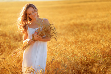 Beautiful young woman in wheat field at sunset outdoor . © Fototocam