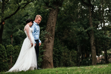Fototapeta premium Beautiful bride and groom hugging and kissing on their wedding day outdoors. Concept wedding, new family.