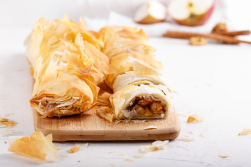 Apple strudel on white table. Homemade pie with apples, walnuts and cinnamon.