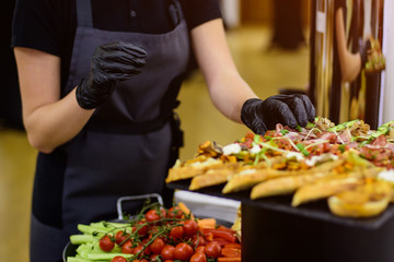 Hands in black gloves serves sandwiches. Catering