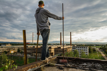 Young man in cap standing and enjoy view to city Ceske Budejovice in sunset with old foundry, Czech republic