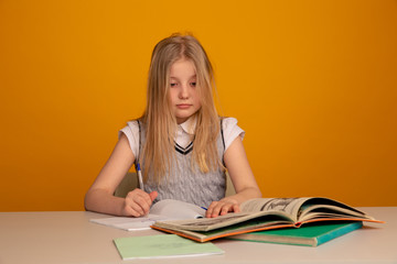 Sad and tired toddler sitting at the desk and doing homework