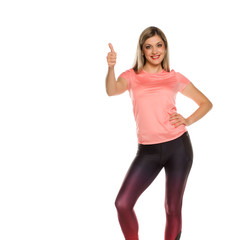 Fototapeta na wymiar Young sporty woman posing with thumbs up on white background