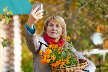 Woman in autumn works in the garden and cleaning leaves.
