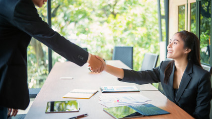Portrait of successful businesswoman shaking hand with professional man while making deal.
